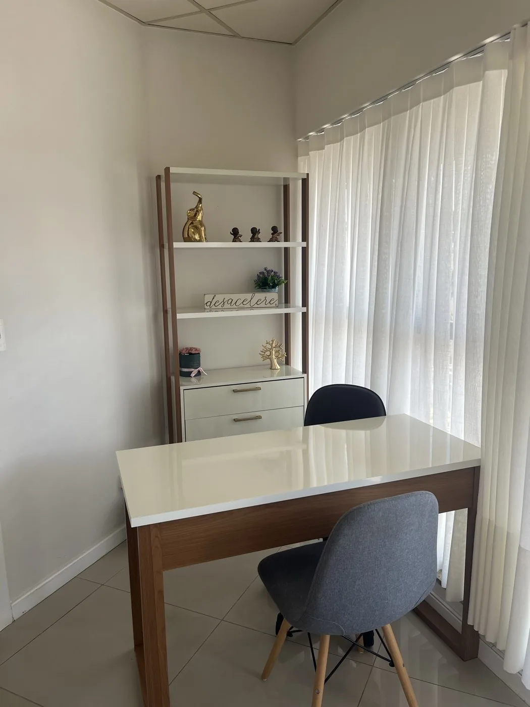 Mesa de trabalho branca com cadeiras e cortina de luz natural